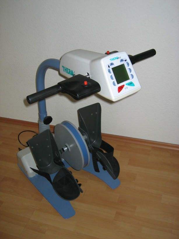 Foto von einem Thera Trainer. Mit einem Rollstuhl kann man an das Gerät heranfahren. Man muss nur die Füße in den Pedalen festmachen und kann im Rollstuhl Fahrrad fahren trainieren.