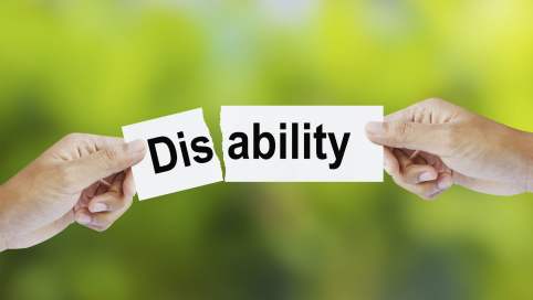 Zwei unterschiedliche Hände zerreissen ein Schriftband zwischen "dis" und "ability" vor einem grünen Hintergrund